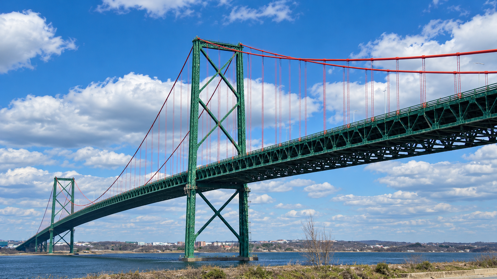 Green suspension bridge in Halifax beneath a blue sky and white clouds.